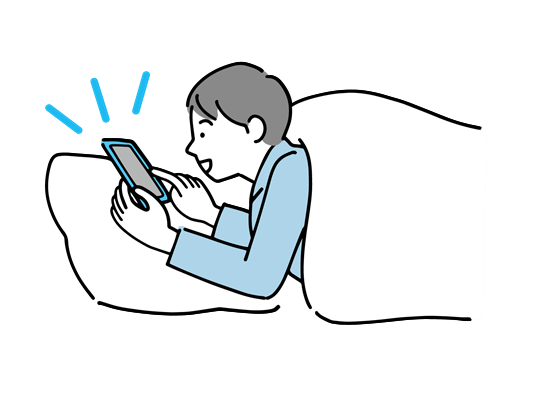 布団の中でスマートフォンを操作する男性